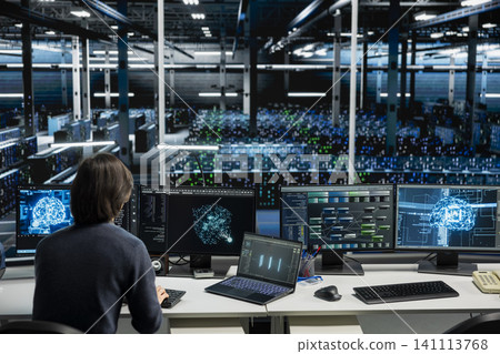 IT specialist working with computer in high tech computing hub with equipment supporting deep learning scientific simulations with computer scientist in server facility doing checkup on rackmounts. 141113768