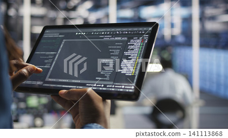 Data center programmer uses a tablet to update server software, supporting reliable infrastructure operations. 141113868