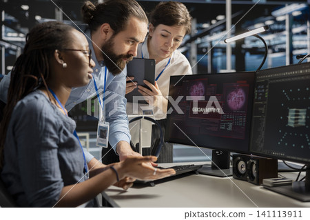 Engineering team reviews a security breach alert for a zero-day vulnerability inside a high-tech server room. Engineering team reviews a security breach alert for a zero-day vulnerability inside a high-tech server room. 141113911