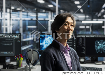 Smiling senior programmer in server room working on databases supporting AI applications. Smiling senior programmer in server room working on databases supporting AI applications. 141113916