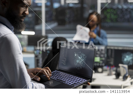 Server room admin working with AI visual analytics tools on laptop to detect hardware faults. 141113954