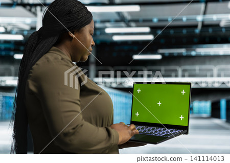 Data center engineer works with a chroma key laptop, using an editable screen to expand workload capacity. 141114013