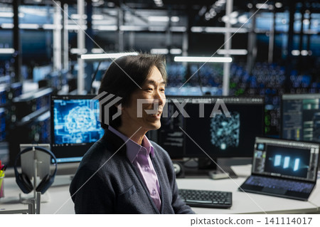 System administrator in server room working with computer, managing AI training data sets. System administrator in server room working with computer, managing AI training data sets. 141114017