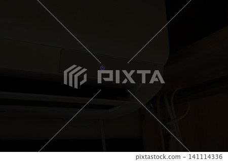 在完全黑暗的房間裡,空調的電源按鈕在夜間會發出藍紫色的光芒。室內空調正在運作。 在完全黑暗的房間裡,空調的電源按鈕在夜間會發出藍紫色的光芒。室內空調正在運作。 141114336