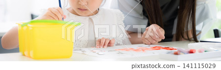 一位大約小學年齡的小女孩在美術課上畫水彩畫,她的母親、老師和一面沒有臉的橫幅在一旁看著。 一位大約小學年齡的小女孩在美術課上畫水彩畫,她的母親、老師和一面沒有臉的橫幅在一旁看著。 141115029