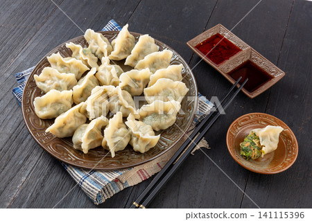 Traditional Chinese pork and shepherd's purse dumplings Jiaozi with dipping sauce and spoon Traditional Chinese pork and shepherd's purse dumplings Jiaozi with dipping sauce and spoon 141115396
