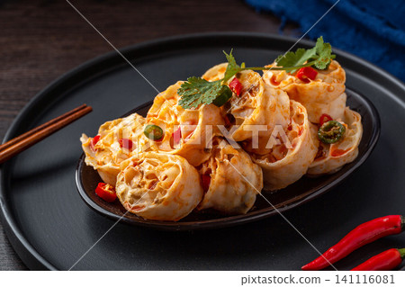 spicy cold wheat gluten noodles served on a black plate with red chili peppers, spicy cold wheat gluten noodles served on a black plate with red chili peppers, 141116081