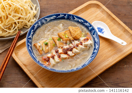 authentic Chinese breakfast tofu soup topped with chili flakes, served in a blue patterned bowl authentic Chinese breakfast tofu soup topped with chili flakes, served in a blue patterned bowl 141116142