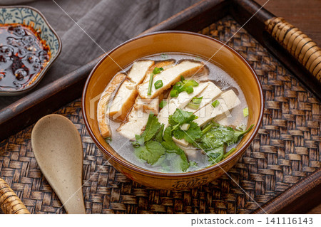 authentic Chinese breakfast tofu soup topped with chili flakes, served in a blue patterned bowl authentic Chinese breakfast tofu soup topped with chili flakes, served in a blue patterned bowl 141116143