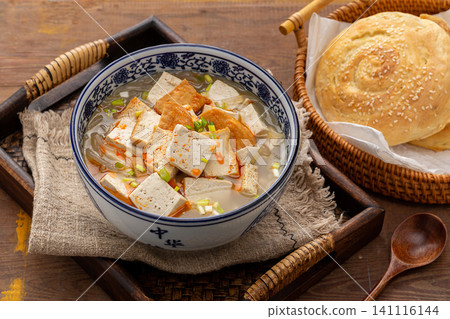 authentic Chinese breakfast tofu soup topped with chili flakes, served in a blue patterned bowl authentic Chinese breakfast tofu soup topped with chili flakes, served in a blue patterned bowl 141116144