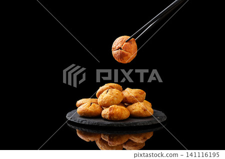 chopsticks holding a crispy Chinese Huangshan mini shaobing pastry over a black background chopsticks holding a crispy Chinese Huangshan mini shaobing pastry over a black background 141116195