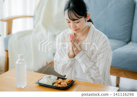 一位年輕女子正在客廳吃午餐 141116298