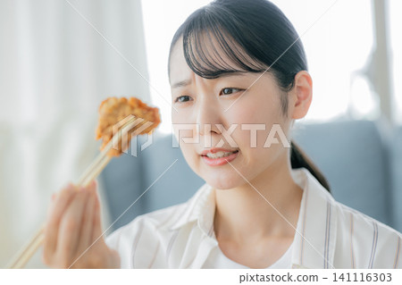 一位年輕女子正在吃炸雞 141116303
