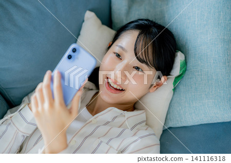 A woman watching a smartphone on a sofa A woman watching a smartphone on a sofa 141116318