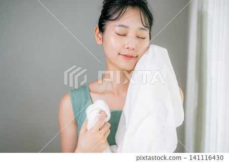 A woman washing her face and wiping it with a towel A woman washing her face and wiping it with a towel 141116430