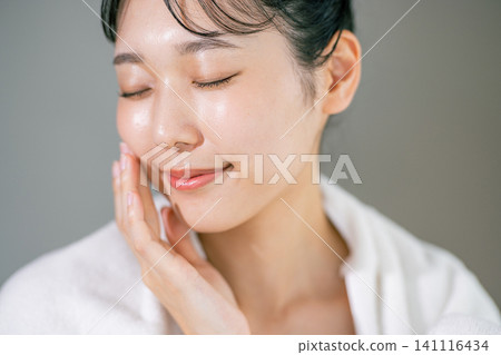 A woman washing her face and wiping it with a towel A woman washing her face and wiping it with a towel 141116434