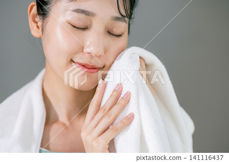 A woman washing her face and wiping it with a towel A woman washing her face and wiping it with a towel 141116437