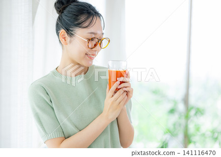 一位年輕女子正在喝番茄汁 141116470