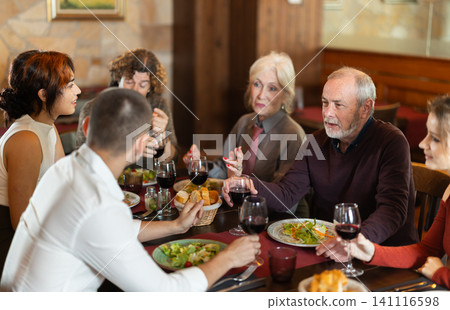 Large friendly family gathered at table to have lunch in restaurant Large friendly family gathered at table to have lunch in restaurant 141116598