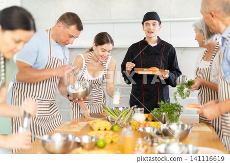 Young chef teaching to cook salmon during group culinary classes Young chef teaching to cook salmon during group culinary classes 141116619