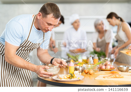 Adult man pouring sauce into dish at master class 141116639