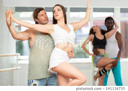 Emotional brunette dancing sensual bachata with male partner in studio Emotional brunette dancing sensual bachata with male partner in studio 141116735