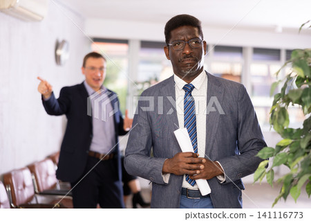 Angry hot-tempered boss shouts yells at hired employee African man in office reception. 141116773
