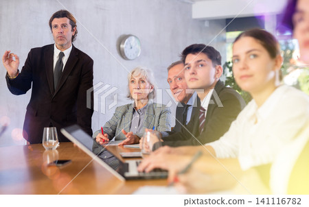 Man top manager standing and confidently speaking during corporate meeting using hand gestures 141116782