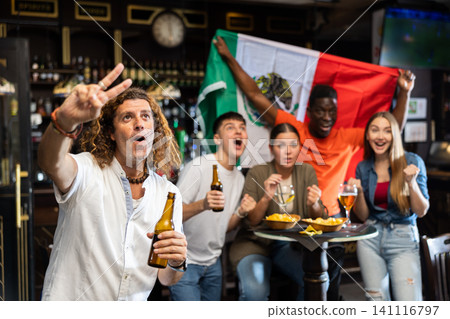Adult man football fan rooting for favorite Mexican team in sports bar 141116797