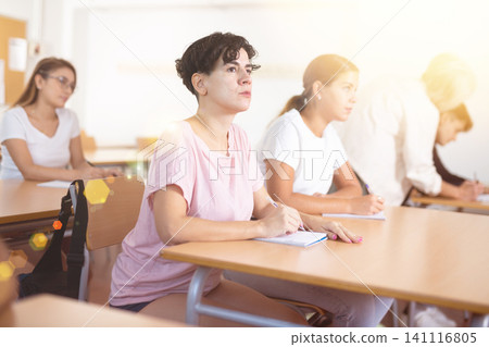 Focused young Chilean woman listening and making notes of lecture Focused young Chilean woman listening and making notes of lecture 141116805