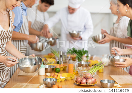 People beating up eggs with whisk at group culinary class 141116979