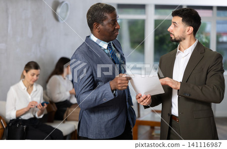 Young businessman with documents talks to male job seeker Young businessman with documents talks to male job seeker 141116987