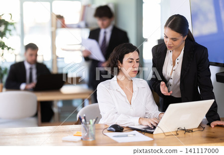 Young woman employee of the bank office helps the woman with work on the laptop 141117000