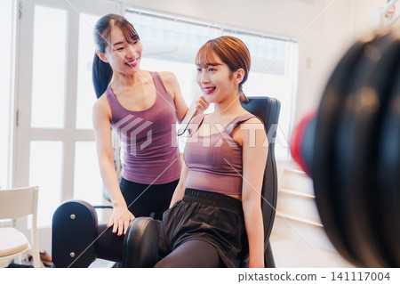 A woman and her coach are training their legs at the gym. A woman and her coach are training their legs at the gym. 141117004