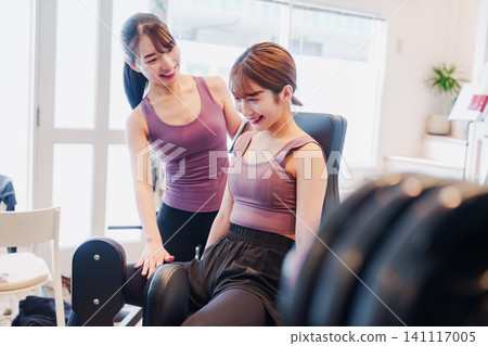 A woman and her coach are training their legs at the gym. A woman and her coach are training their legs at the gym. 141117005