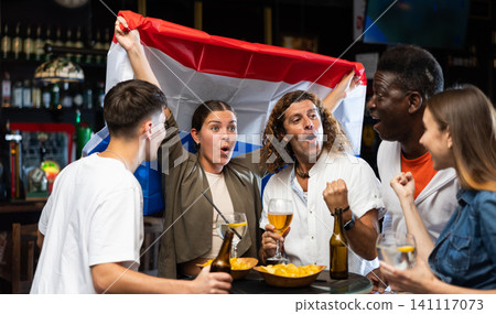 Young adults watching football championship in sports bar, supporting team from Netherlands 141117073