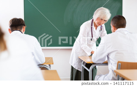 Elderly female professor of medicine giving lecture to students at professional seminar Elderly female professor of medicine giving lecture to students at professional seminar 141117115