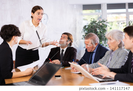 Female corporate worker expressively speaking at team briefing, disagreeing, blaming others Female corporate worker expressively speaking at team briefing, disagreeing, blaming others 141117147