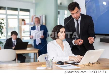 Office employees are working on a project and checking data on a laptop Office employees are working on a project and checking data on a laptop 141117151