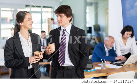 Smiling man and woman colleagues spending free time at coffee break in office 141117154