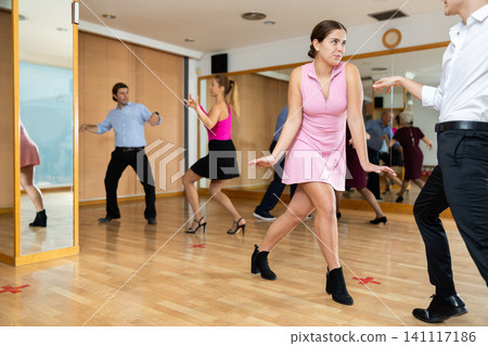 Couple of young dancers rehearsing ballroom dances in dance studio Couple of young dancers rehearsing ballroom dances in dance studio 141117186