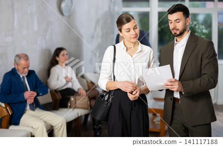 Male HR specialist conducts brief interview with woman applicant in crowded reception room Male HR specialist conducts brief interview with woman applicant in crowded reception room 141117188