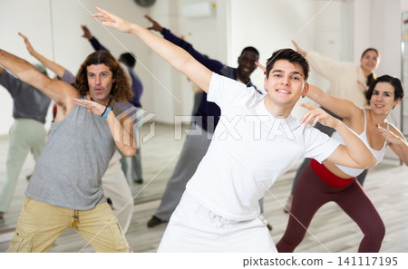 Cheerful guy practicing modern vigorous dance with group Cheerful guy practicing modern vigorous dance with group 141117195