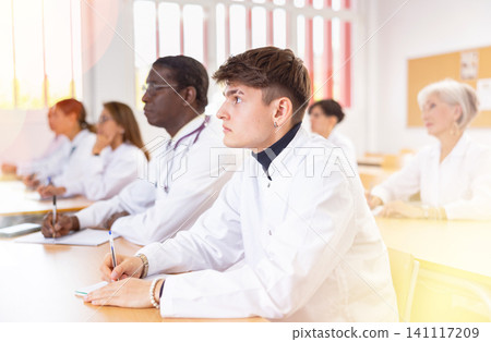 Doctors of different ages sit at their desks and listen carefully to teacher in advanced training class of medical university Doctors of different ages sit at their desks and listen carefully to teacher in advanced training class of medical university 141117209