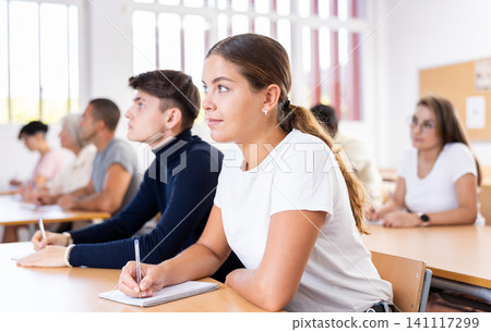 Interested girl listening and taking notes of lecture in university Interested girl listening and taking notes of lecture in university 141117299