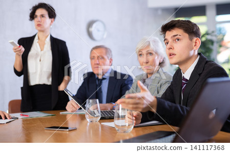 Woman and man sitting at table beside during meeting in conference room Woman and man sitting at table beside during meeting in conference room 141117368