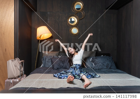 A person stretching on a hotel bed; a relaxed image of a hotel stay. A person stretching on a hotel bed; a relaxed image of a hotel stay. 141117398
