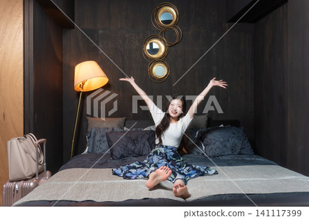 A person stretching on a hotel bed; a relaxed image of a hotel stay. A person stretching on a hotel bed; a relaxed image of a hotel stay. 141117399