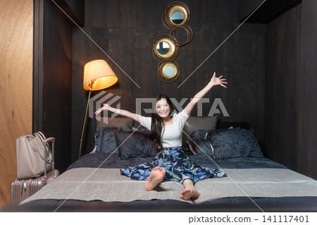 A person stretching on a hotel bed; a relaxed image of a hotel stay. A person stretching on a hotel bed; a relaxed image of a hotel stay. 141117401