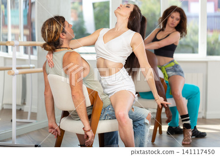 Dark-haired woman practicing lap dance with male partner in studio 141117450